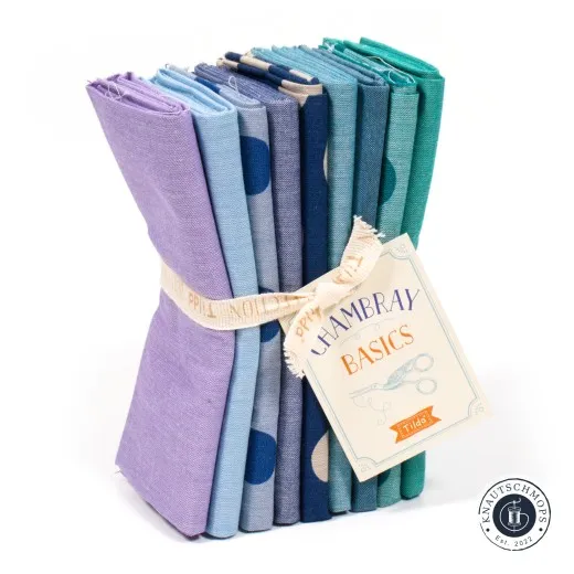 Bundle stehend mit Anhänger Gestapeltes Tilda Fat-Quarter-Bundle „Seasonal Chambray – Summer" in Lila-, Blau-, Petrol- und Smaragdgrüntönen mit Chambray-Basics-Anhänger.