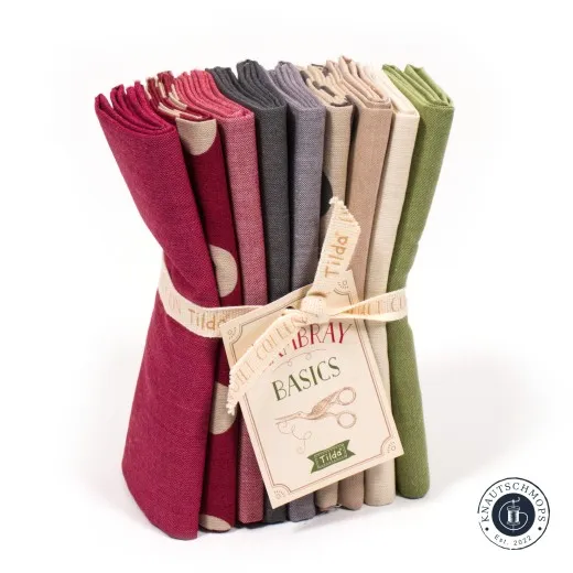 Gestapeltes Tilda Fat-Quarter-Bundle „Seasonal Chambray – Winter" in Beere-, Grau-, Beige- und Grüntönen mit Chambray-Basics-Anhänger.