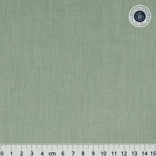 Flach ausgebreiteter, unifarbener Tilda-Chambray-Stoff in Sage mit Lineal zur Maßstabsorientierung.