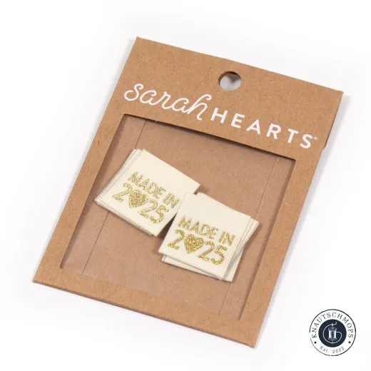 Sarah Hearts Weblabel „Made in 2025“ in Gold auf cremefarbenem Stoff, auf der Verpackungskarte.