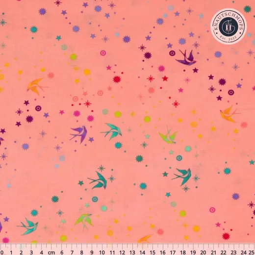 Nahaufnahme des True-Colors-Stoffs „Fairy Dust" in Sherbert mit fliegenden Schwalben und Sternen in Pastelltönen auf hellem Fond, mit Zentimetermaß.