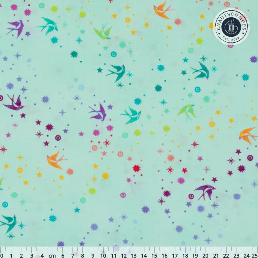 Flach ausgebreiteter Baumwollstoff „Fairy Dust“ in Mint mit Zentimeter-Maßstab: bunte Schwalben und Sternchen-Konfetti auf Mintgrün.