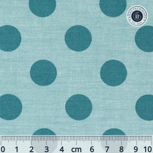 Nahaufnahme des Tilda-Musters „Chambray Dots" in Aqua mit petrolfarbenen, ca. 18mm großen Punkten auf meliertem hellblauem Chambray-Fond, mit Maßband zum Größenvergleich.