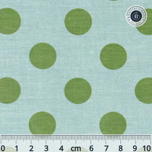 Nahaufnahme des Tilda-Musters „Chambray Dots" in Tealgreen mit olivgrünen, ca. 18mm großen Punkten auf meliertem türkisem Chambray-Fond, mit Maßband zum Größenvergleich.