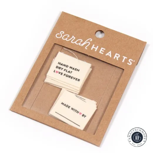 Sarah Hearts Bio-Baumwoll-Weblabel „Hand Wash, Dry Flat, Love Forever“ auf der Original-Verpackungskarte.