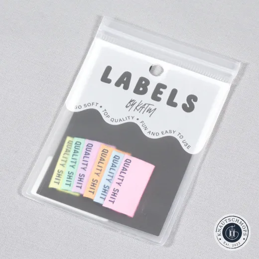 Verpackung der KATM-Labels Quality Shit in Pastellfarben mit sechs sichtbaren Labels, Ansicht schräg von oben