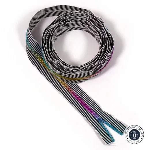 Aufgerolltes Reißverschlussband Nr. 5 mit schwarz-weißem Streifenmuster und mehrfarbiger Regenbogen-Zähnereihe, freigestellt auf weißem Hintergrund.