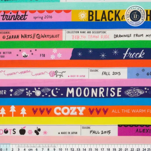 Musterausschnitt mit bunten Streifen im Webkanten-Design, bedruckt mit Kollektionsnamen und Schriftzügen wie „Moonrise" und „Cozy".