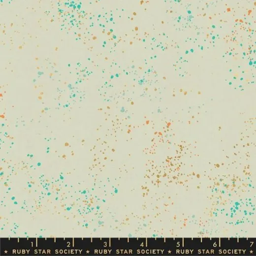 Speckled Shell – Musternahaufnahme Nahaufnahme des Ruby Star Society Speckled Stoffs in Shell: cremefarbener Fond mit türkisen, orangefarbenen und goldenen Farbsprenkeln, Marken-Maßband zeigt die Musterdichte.