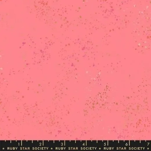 Speckled Sorbet – Stoffdetail Nahaufnahme des melierten Baumwollstoffs Speckled in Sorbet mit goldmetallic- und pinkfarbenen Farbspritzern auf zartem Rosa, mit Maßband am Bildrand.