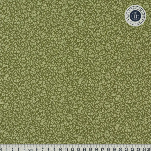 Stoffdetail mit Maßband Detailaufnahme des Tilda-Baumwollstoffs „Merry Little Christmas – Blender“ in Eve Pine mit Zentimeter-Maßband zur Größeneinschätzung des kleinteiligen Blätterdrucks.