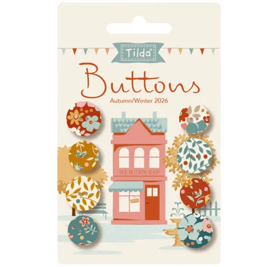 Verpackungskarte mit 8 Tilda-Knöpfen der Kollektion Village Life in Rost- und Ochertönen vor einer Illustration eines rosa Ladengeschäfts.