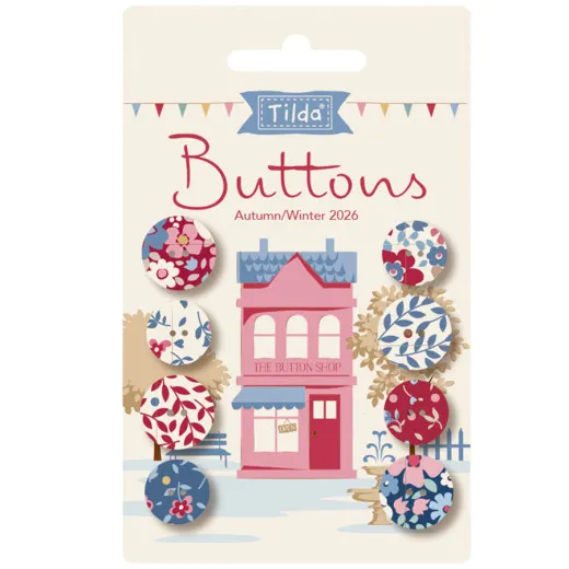 Verpackungskarte mit 8 Tilda-Knöpfen der Kollektion Village Life in Bordeaux- und Blautönen vor einer Illustration eines rosa Ladengeschäfts.