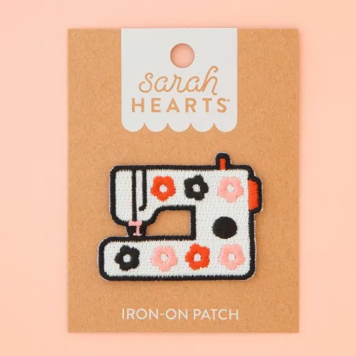 Verpackung des Sarah Hearts Aufnähers „Nähmaschine" mit weißer Retro-Nähmaschine und buntem Blumenmuster.