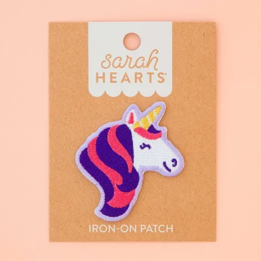 Verpackung Frontalansicht Verpackung des Sarah Hearts Aufnähers „Unicorn" mit lila-pinkfarbenem Einhornkopf und goldenem Horn auf Kraftpapier-Karte.