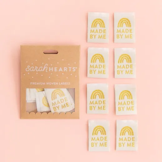 Kraftpapier-Verpackung der Sarah Hearts Weblabels "Made by Me" mit Regenbogen-Motiv in goldenem Glitzerfaden auf cremefarbenem Hintergrund.