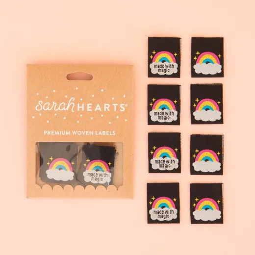 Verpackung der Sarah Hearts Weblabel „Made with Magic" mit acht schwarzen Labels, goldfarbenem Regenbogen und Wolke.