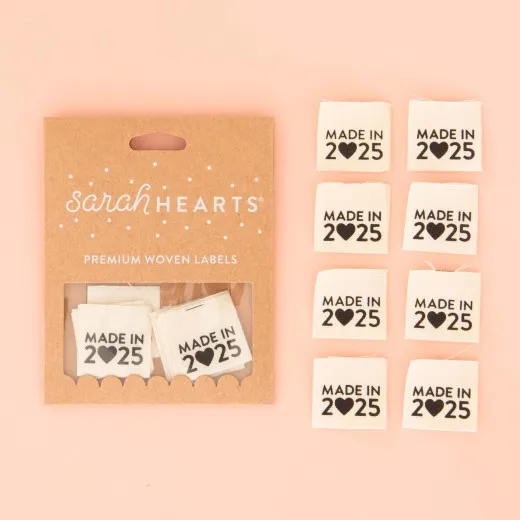 Verpackung mit allen Labels Sarah-Hearts-Verpackung „Made in 2025" aus Bio-Baumwolle in Schwarz-Weiß, daneben alle acht Endfalt-Weblabel.