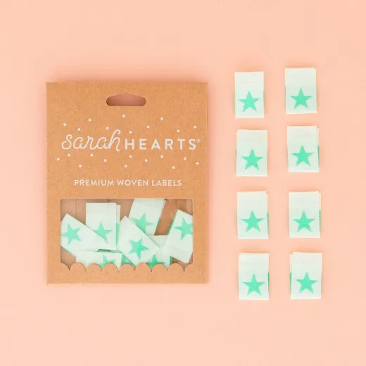 Sarah-Hearts-Verpackung „Star" in Mint, daneben alle acht Weblabel aus weichem Polyester.