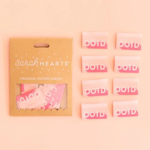 Sarah-Hearts-Weblabel „OOTD" in Kraftpapier-Verpackung neben allen acht rosa Labels mit pinkfarbenem Verlauf.