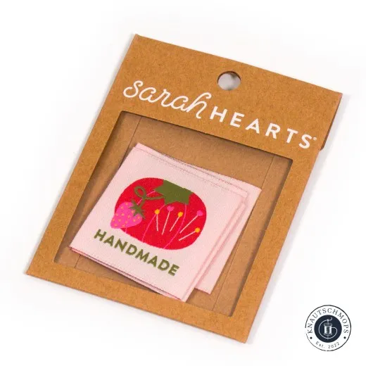 Sarah Hearts Weblabel „Tomato Pin Cushion Handmade“ mit Nadelkissen-Motiv, sichtbar durch das Fenster der Verpackung.