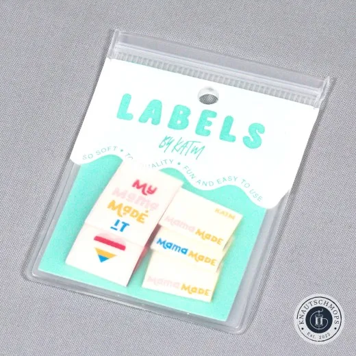 Verpackung My Mama Made It Verpackte Kylie and The Machine Label-Sets „My Mama Made It" und „Mama Made" mit Herz-Symbol auf türkisfarbener Verpackungskarte.