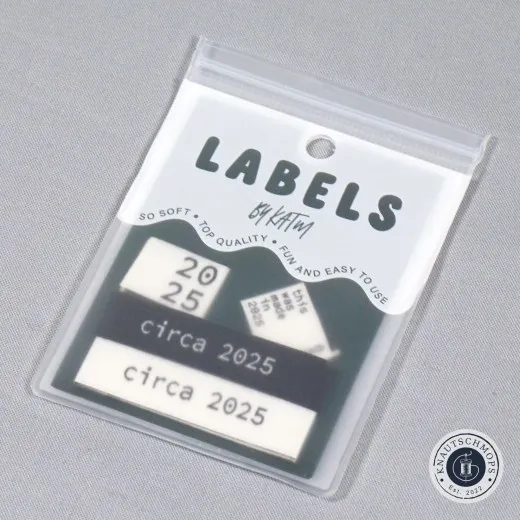 Jahresstempel-Set „Circa 2025" mit Jahreszahl-Label, Mini-Etikett „this was made in 2025" und „circa 2025"-Labels in Schwarz/Creme, sichtbar in der Verpackungskarte, schräg fotografiert.