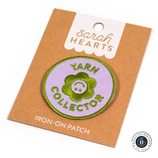 Verpackung schräge Ansicht Sarah Hearts Iron-On Patch „Yarn Collector" mit Blüten-Smiley auf lila Rundpatch, schräg auf der Verpackungskarte fotografiert.
