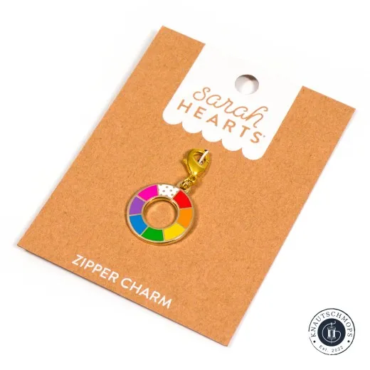 Verpackung schräge Ansicht Sarah Hearts Zipper Charm „Color Wheel" mit buntem Farbrad-Design und goldenem Karabiner, schräg auf der Verpackungskarte fotografiert.