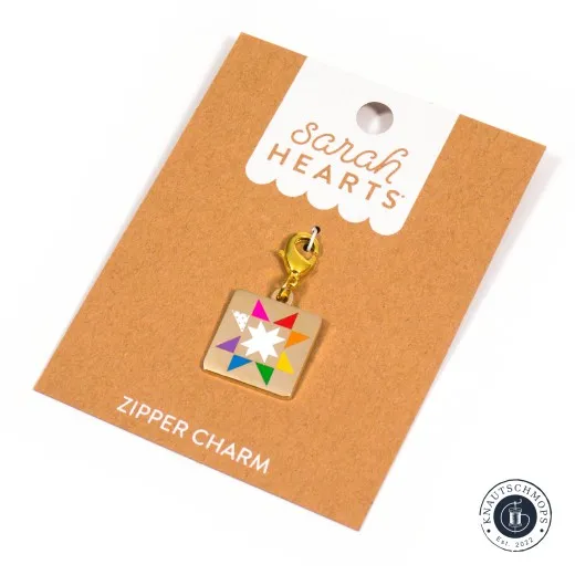 Verpackung schräge Ansicht Sarah Hearts Zipper Charm „Quilt Star" mit buntem Sternmuster und goldenem Karabiner, schräg auf der Verpackungskarte fotografiert.
