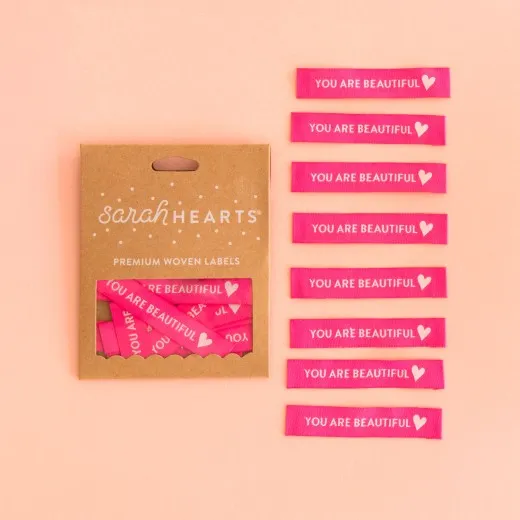 Verpackung You are Beautiful Labels Sarah Hearts Verpackungskarton mit 8 pinken Band-Weblabels, weißer Schriftzug „You are Beautiful" mit Herz-Symbol.