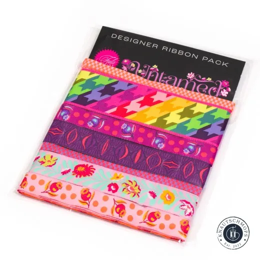 Verpackung des Tula-Pink-Webband-Sets „Untamed" in Cosmic mit sieben unterschiedlich breiten Bändern in Pink-, Orange- und Lilatönen.