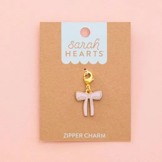 Sarah Hearts Zipper Charm „Pink Bow“ in Form einer rosa Emaille-Schleife mit goldenem Karabiner.