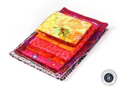 Stapel aus zehn bedruckten Baumwollstoffen des Kaffe Fassett Collective in Pink, Rot, Orange und Gelb