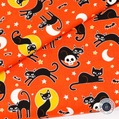 Gefalteter Halloweenstoff mit schwarzen Katzen, Fledermäusen und Monden auf orangem Grund in Nahaufnahme
