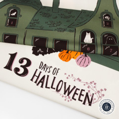 Aufgerollter Baumwollstoff mit Spukhaus-Motiv und Schriftzug 13 Days of Halloween in Schwarz und Rosa