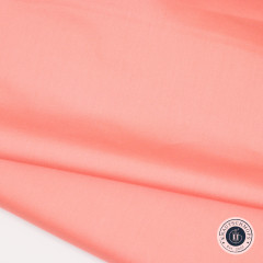Apricot-farbener Stoff mit leichtem Glanz und Faltenwurf, Nahaufnahme der Stoffstruktur