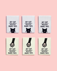 Drei Labels mit Katzengesicht und drei mit Pfotenabdruck-Motiv nebeneinander auf rosa Hintergrund.