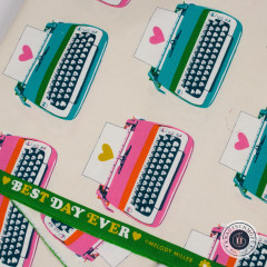 Grünes Ripsband mit dem Schriftzug „Best Day Ever ♥ Melody Miller“ auf dem cremefarbenen Schreibmaschinen-Canvas drapiert.