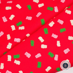 Diagonal gefalteter roter Baumwollstoff mit gestreuten Gummibärchen in Rosa, Creme und Grün