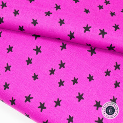 Gefalteter pinker Baumwollstoff mit schwarzen Sternen in Nahaufnahme