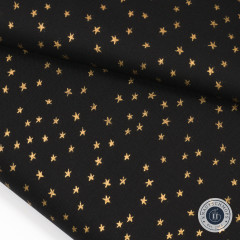 Nahaufnahme des gefalteten Stoffes Mini Starry mit goldglänzenden Sternen auf schwarzem Baumwollgrund