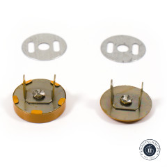 Zwei senfgelbe Druckknöpfe von der Metallrückseite gezeigt mit Splinten, Schraubverschluss und den passenden Unterlegscheiben.