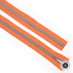 Zwei diagonal ausgelegte Längen des orange-weiß gestreiften Reißverschlussbandes mit silberner Zahnreihe auf weißem Hintergrund.