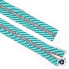 Zwei parallel liegende Streifen des Teal-Stripe-Reißverschlussbands mit silberfarbenen Spiralzähnen in Nahaufnahme.