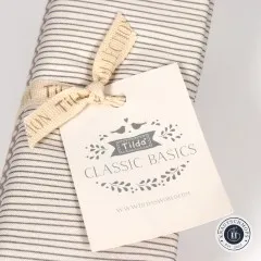 Nahaufnahme des Tilda-„Classic Basics“-Anhängers auf dem gestreiften Stoff des Grey-Bundles.