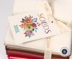 Nahaufnahme des „Solids"-Anhängers auf cremefarbenem Stoff