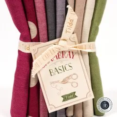 Nahaufnahme des Papieranhängers „Chambray Basics" mit grünem Tilda-Logo neben Beere- und Grau-Stoffkanten.
