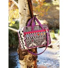 Eine fertige Tasche im Schwarz-Weiß-Pfauendesign, an einem Baumstamm im Freien aufgehängt.