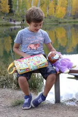 Kind mit genähter Changing-Station-Clutch im Blumenmuster im Freien